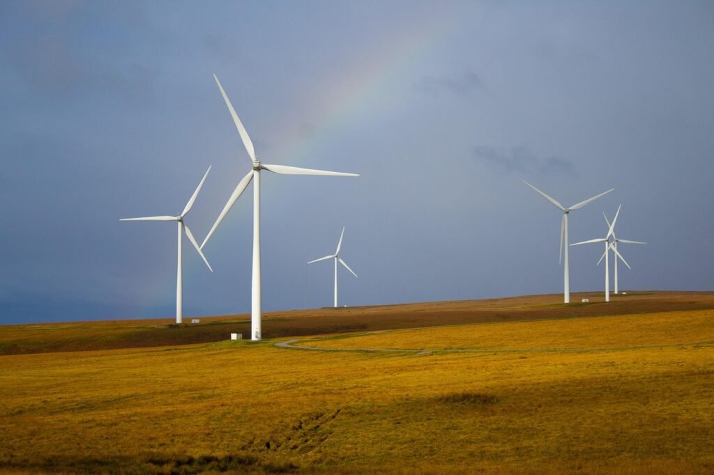 Wind turbines operating across open fields under a cloudy sky.